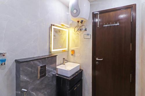 a bathroom with a sink and a wooden door at Frankstay By Hotel Samrat Residency 10 Mints Walking Distance Nizamuddin Railway Station in New Delhi