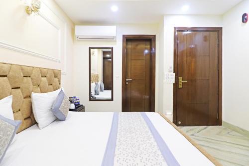 a bedroom with a large white bed and a wooden door at Frankstay By Hotel Samrat Residency 10 Mints Walking Distance Nizamuddin Railway Station in New Delhi