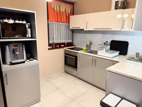 a kitchen with white cabinets and a sink at Éjjelibagoly Vendégház in Szentes