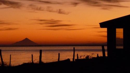 a sunset over the water with a mountain in the background at Beach House Hideaway in Lechagua