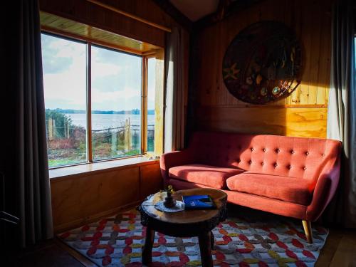 a living room with a red couch and a large window at Beach House Hideaway in Lechagua
