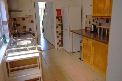 a small kitchen with a sink and a refrigerator at Stylish 3-Bed Swansea Home with WiFi & Kitchen in Swansea