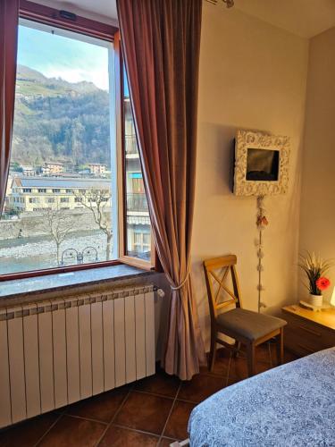 a bedroom with a large window and a chair at Baciati dal Sole-Self check-in in San Pellegrino Terme