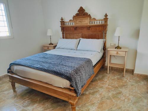 a bedroom with a large bed with a wooden headboard at La campagne à 10 mn des plages et du centre ville de Cartagena in Cartagena