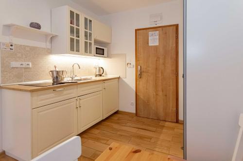 a kitchen with white cabinets and a wooden door at Resort Mlýn Karolínka in Vranov nad Dyjí