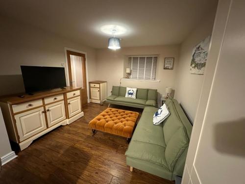 a living room with a green couch and a flat screen tv at Pebble Cottage in Golspie