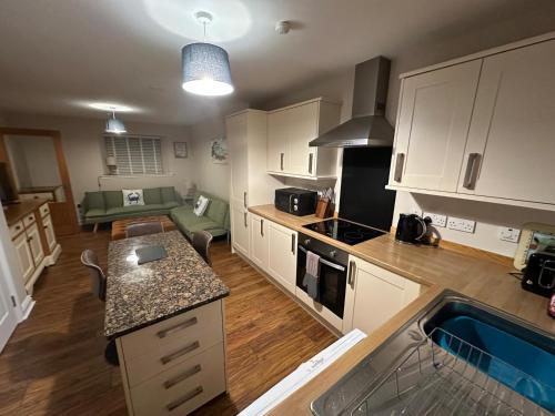 a kitchen with white cabinets and a living room at Pebble Cottage in Golspie