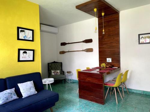 ein Wohnzimmer mit einem blauen Sofa und einer gelben Wand in der Unterkunft CoCo Cozy Apartment Centric and Private in Cozumel