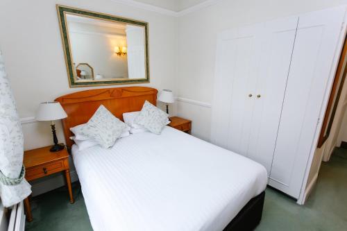 a bedroom with a white bed and a mirror at The Snooty Fox in Tetbury
