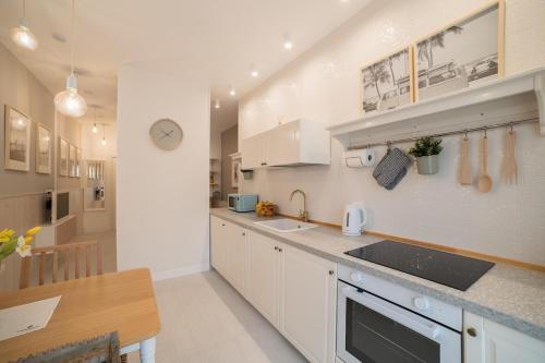a kitchen with white cabinets and a sink and a table at Leopardi Al Mare Nuovissimo in Alba Adriatica