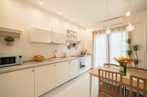a kitchen with white cabinets and a wooden table at Leopardi Al Mare Nuovissimo in Alba Adriatica
