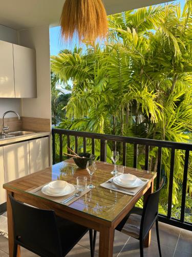 a wooden table with two chairs and a kitchen with palm trees at Studio Atoumo Marine 5 in Saint-François