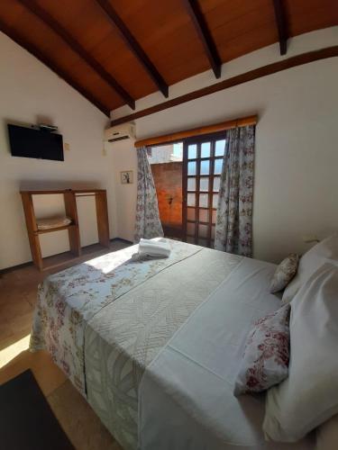 a bedroom with a large bed with a window at Pousada Ikabana in Pirenópolis