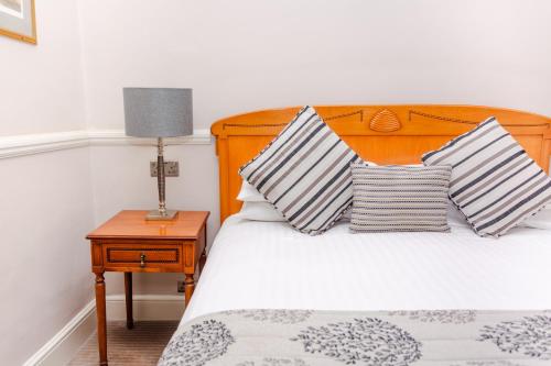 a bed with two pillows and a lamp on a table at The Snooty Fox in Tetbury