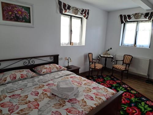 a bedroom with a bed and two chairs and windows at Casa Delia in Mănăstirea Humorului