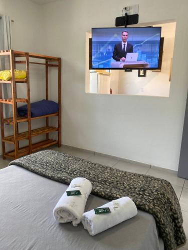 a room with a bed with towels and a flat screen tv at Hospedagem Vista do Sol in Cachoeira do Sul