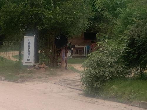 a sign in front of a tree with a house at Cabanas Parparim in Mina Clavero