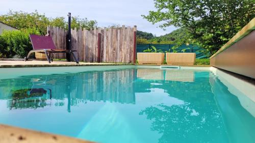 a swimming pool with blue water and a wooden fence at Le Quai in Saint-Vincent-de-Cosse