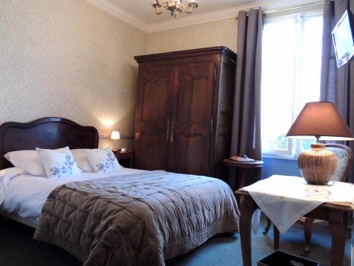 a bedroom with a bed with a wooden headboard and a window at La Villa Bois Joli HOTEL RESTAURANT in Bagnoles de l'Orne