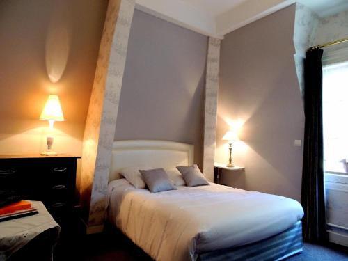 a bedroom with a large bed with two lamps at La Villa Bois Joli HOTEL RESTAURANT in Bagnoles de l'Orne