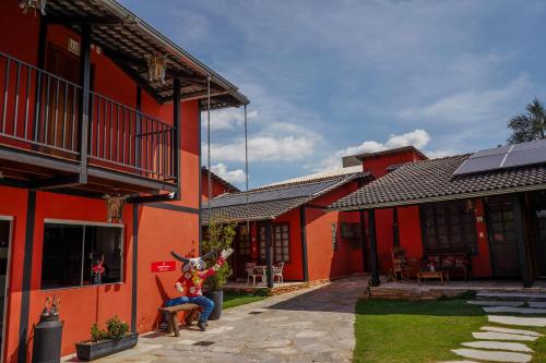 a woman sitting on a chair in front of a red building at Pousada Ikabana in Pirenópolis