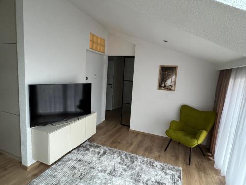 a living room with a television and a green chair at Apartments HAN 2 Sarajevo in Sarajevo