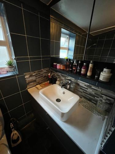 Un baño con un lavabo blanco y un espejo. en room near Luton center, en Luton