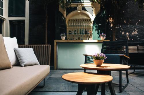 a patio with a couch and two tables at The Dylan Amsterdam - The Leading Hotels of the World in Amsterdam