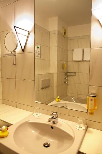 a bathroom with a sink and a mirror and a tub at Best Western Hotel Heide in Oldenburg