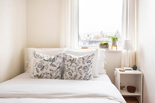 a bed with white sheets and pillows in front of a window at Private room with views to the mountains in Reykjavík