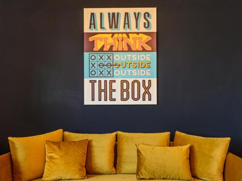 un canapé avec des oreillers jaunes contre un mur bleu dans l'établissement KOA - THE BOX, à Braşov