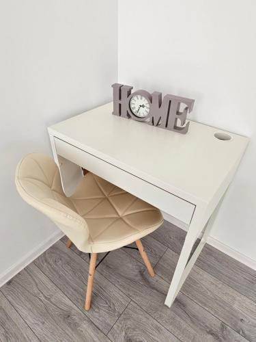 a white desk with a clock and a chair at ByaResidence in Valea Lupului