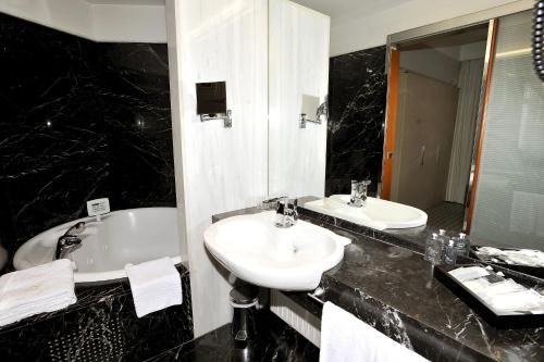 a black and white bathroom with two sinks and a tub at Gran Hotel Albacete in Albacete