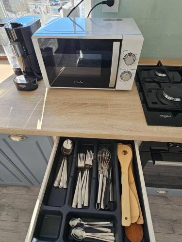 a drawer in a kitchen with a microwave and utensils at ByaResidence in Valea Lupului