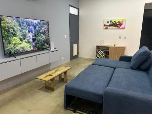 a living room with a blue couch and a tv at Bravo paraiso azul beach house in Savegre