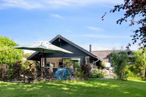 a house with an umbrella in a yard at The Summer House In Peaceful Nyrup in Nykøbing Sjælland