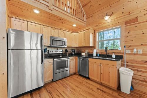a kitchen with wooden cabinets and a stainless steel refrigerator at Cabin 4 Mtn View Cabin Near River with Fire Pit and Hot Tub in Jasper