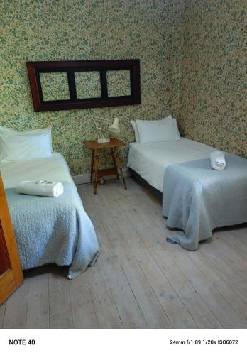a bedroom with two beds and a table and a window at Robertson Victoriaan in Robertson