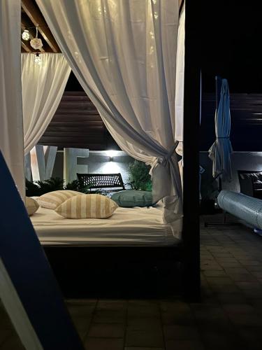 a bed with white curtains in a room at Kuća za odmor Mladen i Martina in Slavonski Brod