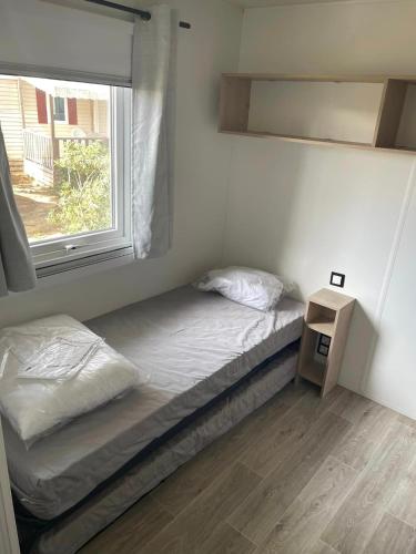 une petite chambre avec un lit et une fenêtre dans l'établissement Mobil-home premium 325, à Narbonne