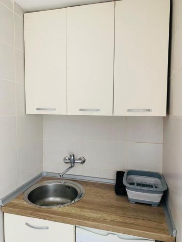 um balcão de cozinha com um lavatório e armários brancos em Laki's House em Mavrovo