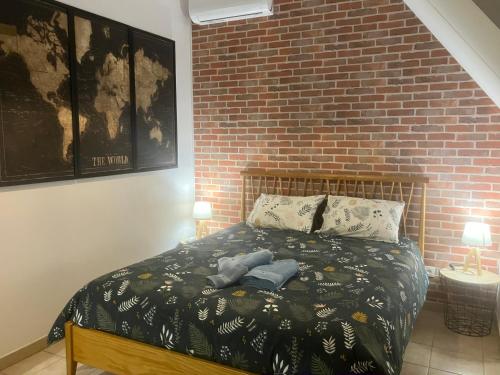 une chambre avec un lit avec un mur de briques dans l'établissement Le N5 des Hauts de Sarlat Apt Duplex Clim, Piscine, Parking, à Sarlat-la-Canéda