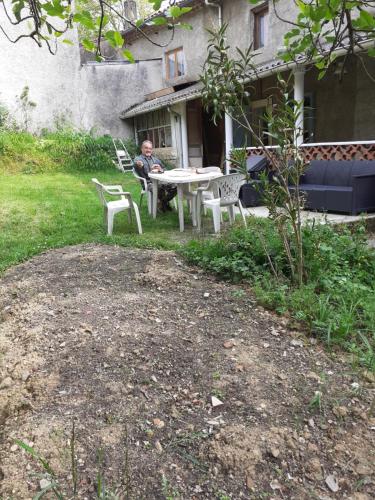 un homme assis à une table dans une cour dans l'établissement Maison calme, à Payrin-Augmontel