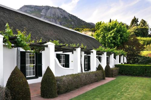 an exterior view of a white house with a garden at Grande Roche Hotel in Paarl