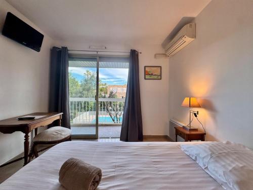 une chambre avec un lit, un bureau et une fenêtre dans l'établissement Le Lys - Apt 4 Prs - clim - piscine - parking, à Antibes