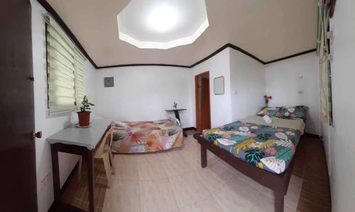 a room with two beds and a table in it at Subangan sa Adlaw 5 in Burgos