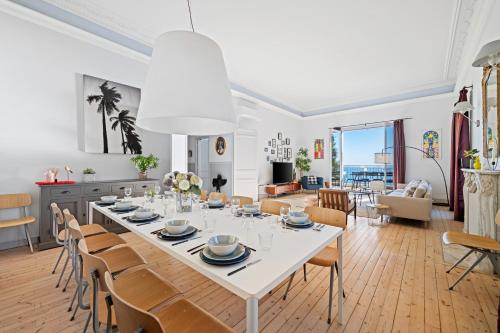 une salle à manger et un salon avec une table et des chaises blanches dans l'établissement Magnifique Villa d'époque vue mer, plage à 12 min à pieds, à Menton