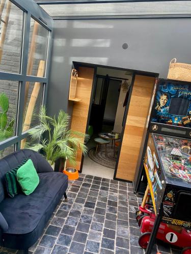 a living room with a pinball machine and a couch at Maisonette jacuzzi terrasse Lille in Saint-André-lez-Lille