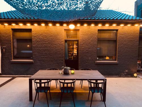 a wooden table and chairs in front of a building at Maisonette jacuzzi terrasse Lille in Saint-André-lez-Lille