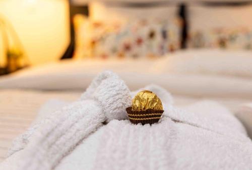 a white towel with a gold object on a bed at Maisonette jacuzzi terrasse Lille in Saint-André-lez-Lille